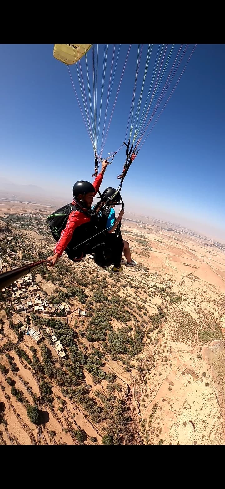 Parapentiste en vol au-dessus de l’Atlas marocain, ciel nuageux dramatique